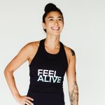 Woman wearing a black tank top with "Feel Alive" on the front.